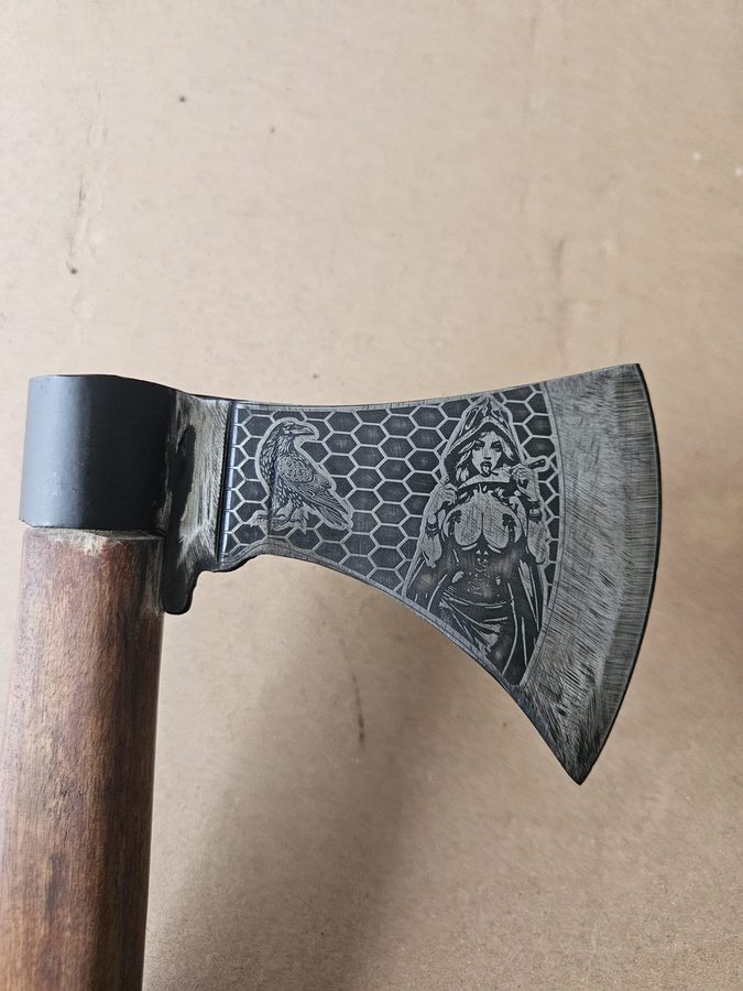 Norse-themed axe head engraved with a raven and a shieldmaiden